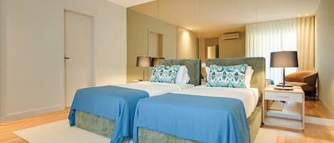 A hotel room with two beds, a nightstand, a lamp, and a mirror.