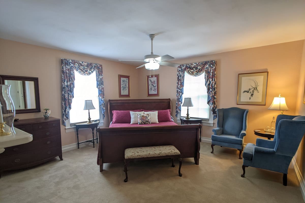 A bedroom with a bed, a chair, a dresser, and a ceiling fan.
