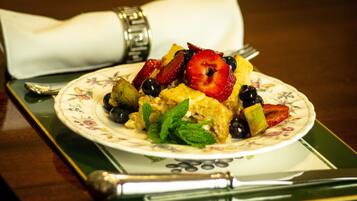 A plate of food with strawberries, blueberries, and mint leaves on a floral-patterned plate.