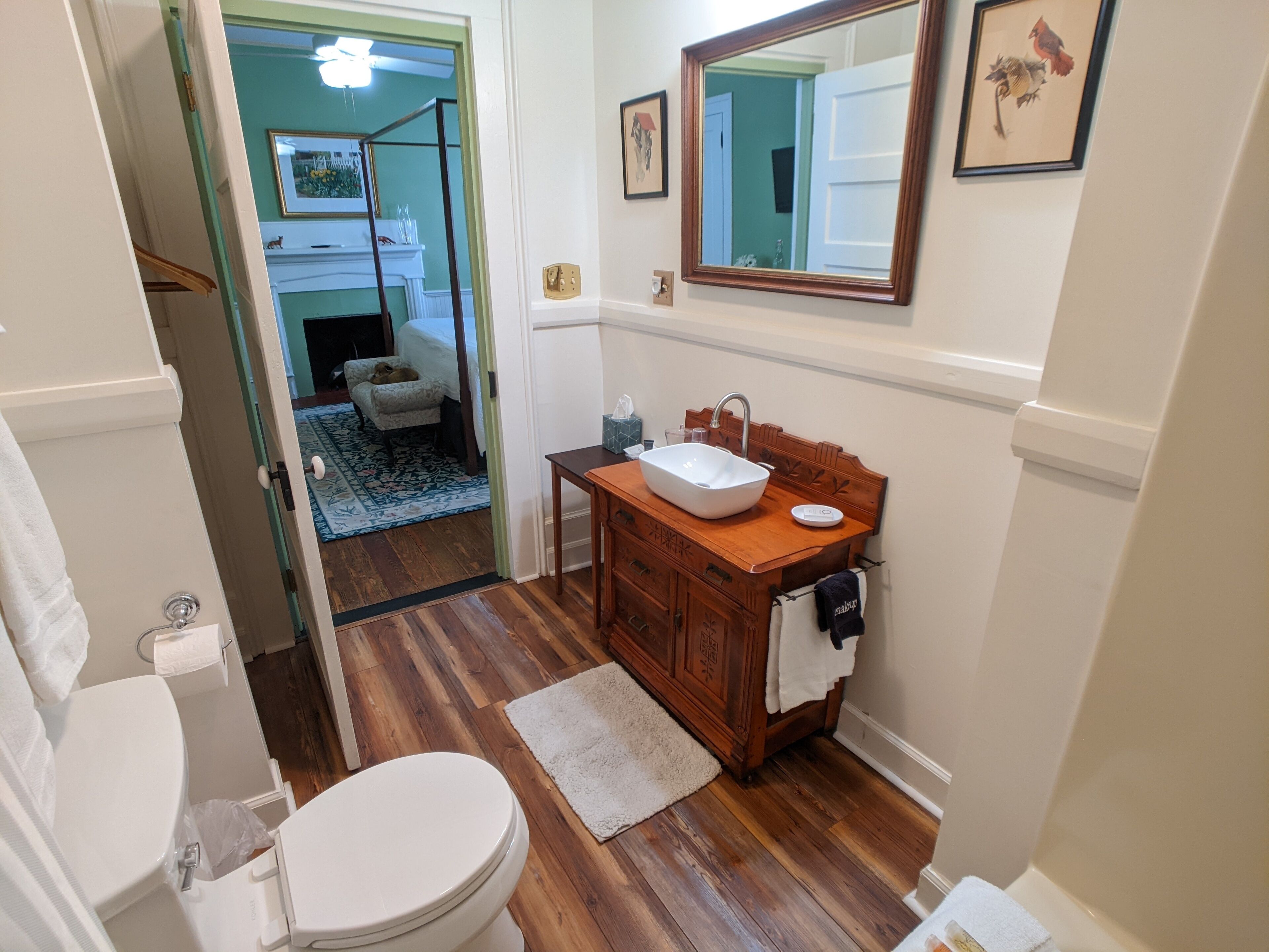 A bathroom with a wooden vanity, white sink, and a mirror above it.