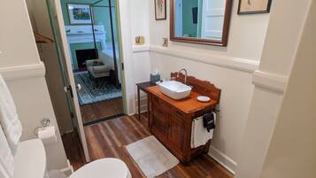 A bathroom with a wooden vanity, white sink, and a mirror above it.