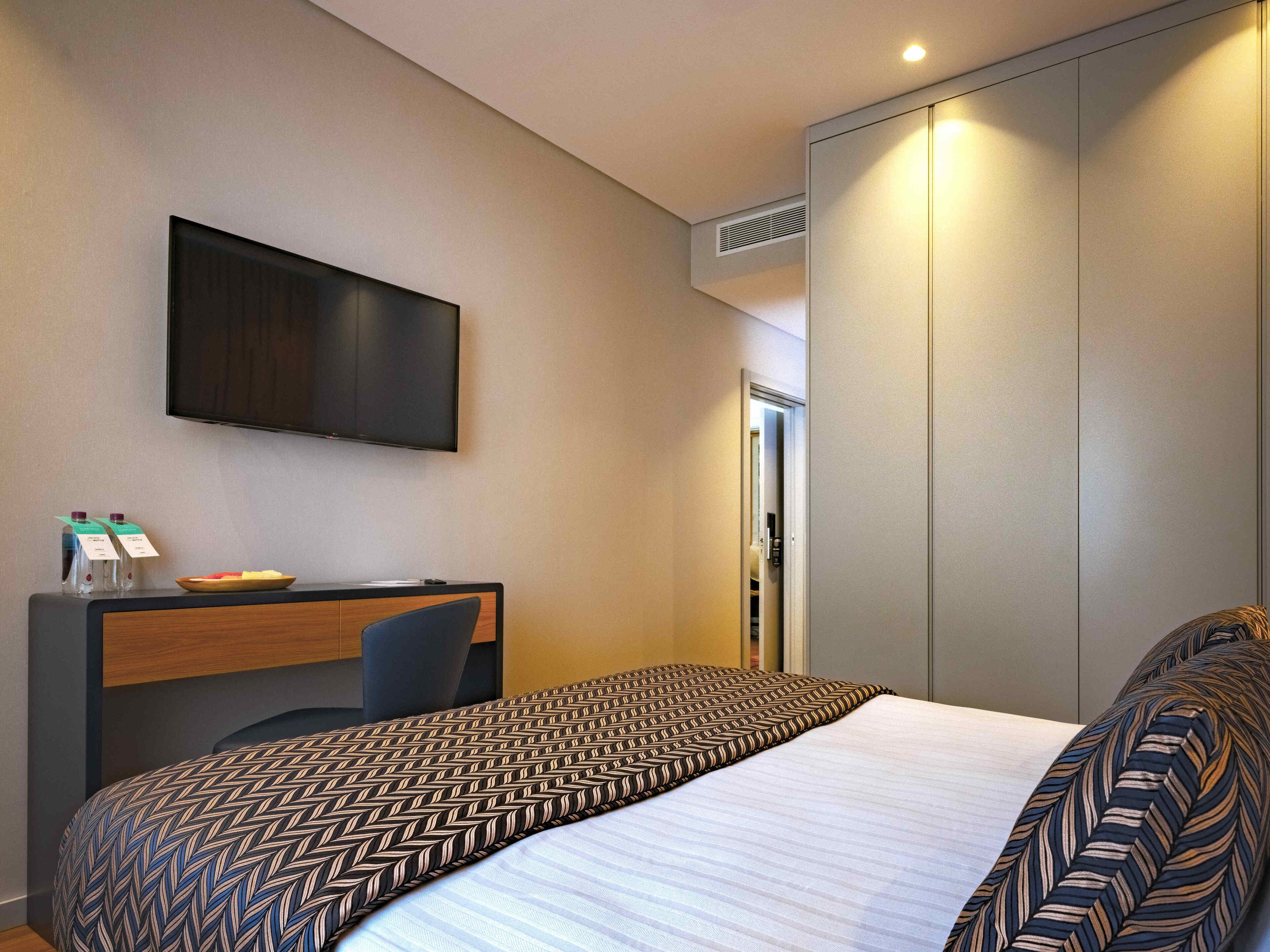 Ein Hotelzimmer mit Bett, Schreibtisch, Fernseher und Kleiderschrank.
