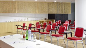 Una sala de conferencias con una larga mesa, sillas rojas y un panel de pared de madera.