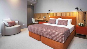 Un dormitorio moderno con una cama grande, un escritorio, una silla y una mesita de noche.
