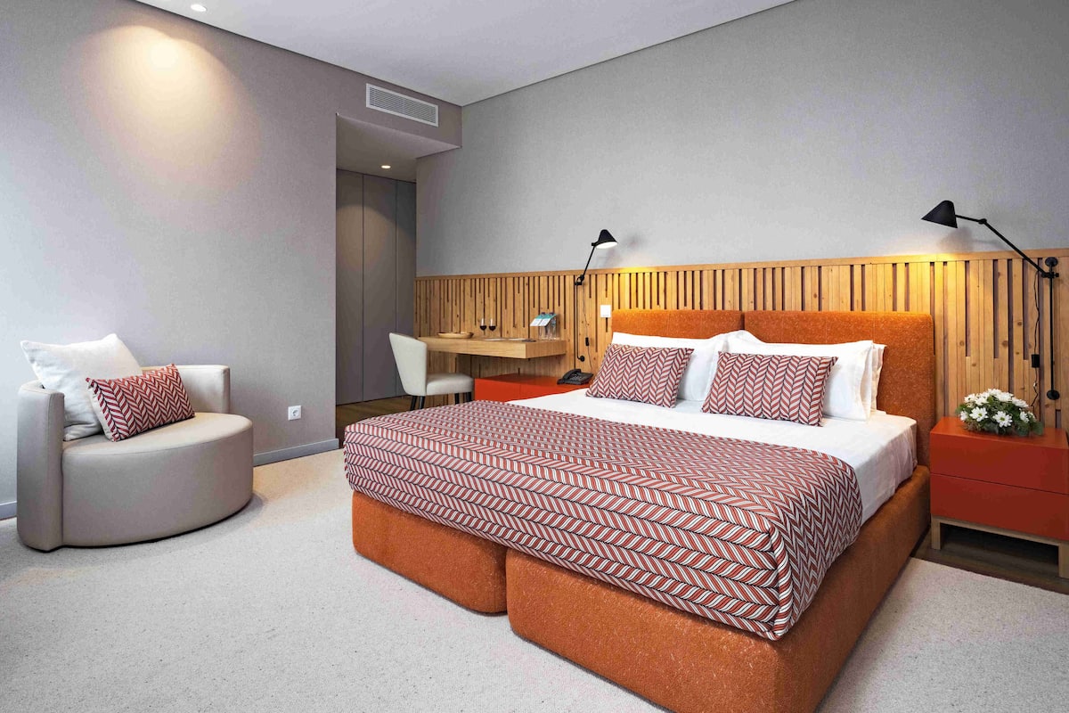 Un dormitorio moderno con una cama grande, un escritorio, una silla y una mesita de noche.