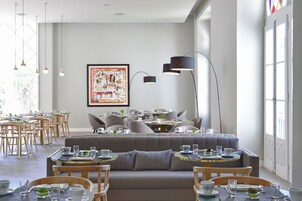 Un comedor moderno con mesas redondas, asientos acolchados e iluminación colgante.
