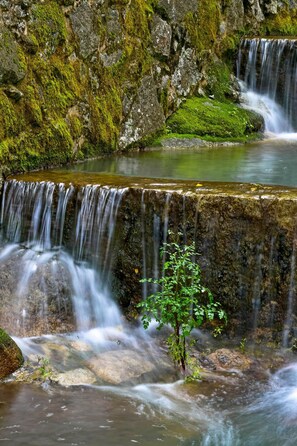A waterfall cascading over moss-covered rocks into a calm pool. - Central Monchique Hotel by Unlock Hotels (Monchique)