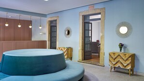 Quarto moderno com sofá azul, mobiliário de madeira e iluminação pendente.