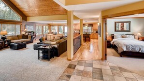 A spacious living area with a large window, a sofa, a coffee table, and a dining area with a table and chairs. - Evergreen Mountain Lodge (Cle Elum)