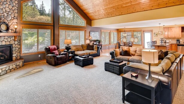A spacious living room with large windows, a stone fireplace, and a cozy seating area. - Evergreen Mountain Lodge (Cle Elum)