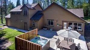 A two-story wooden house with a patio area, including a hot tub, outdoor seating, and a covered table. - Evergreen Mountain Lodge (Cle Elum)