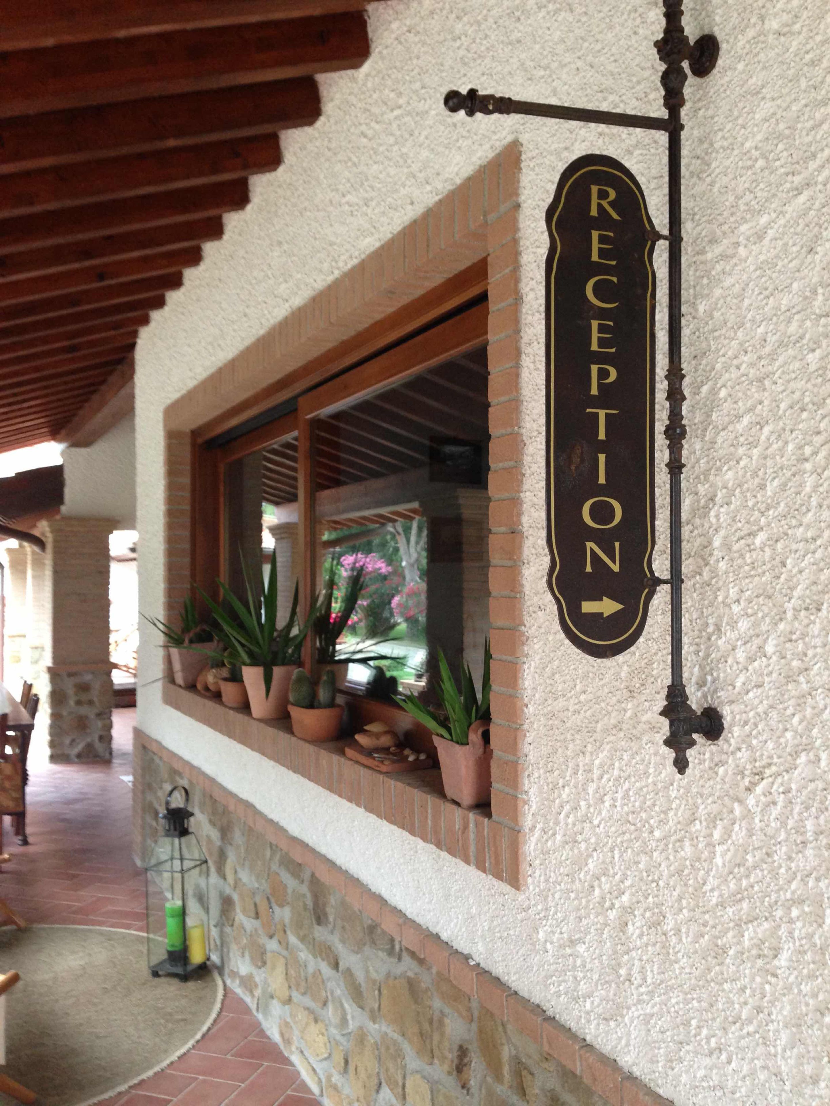 A reception sign with a directional arrow, a window with potted plants, and a stone wall.