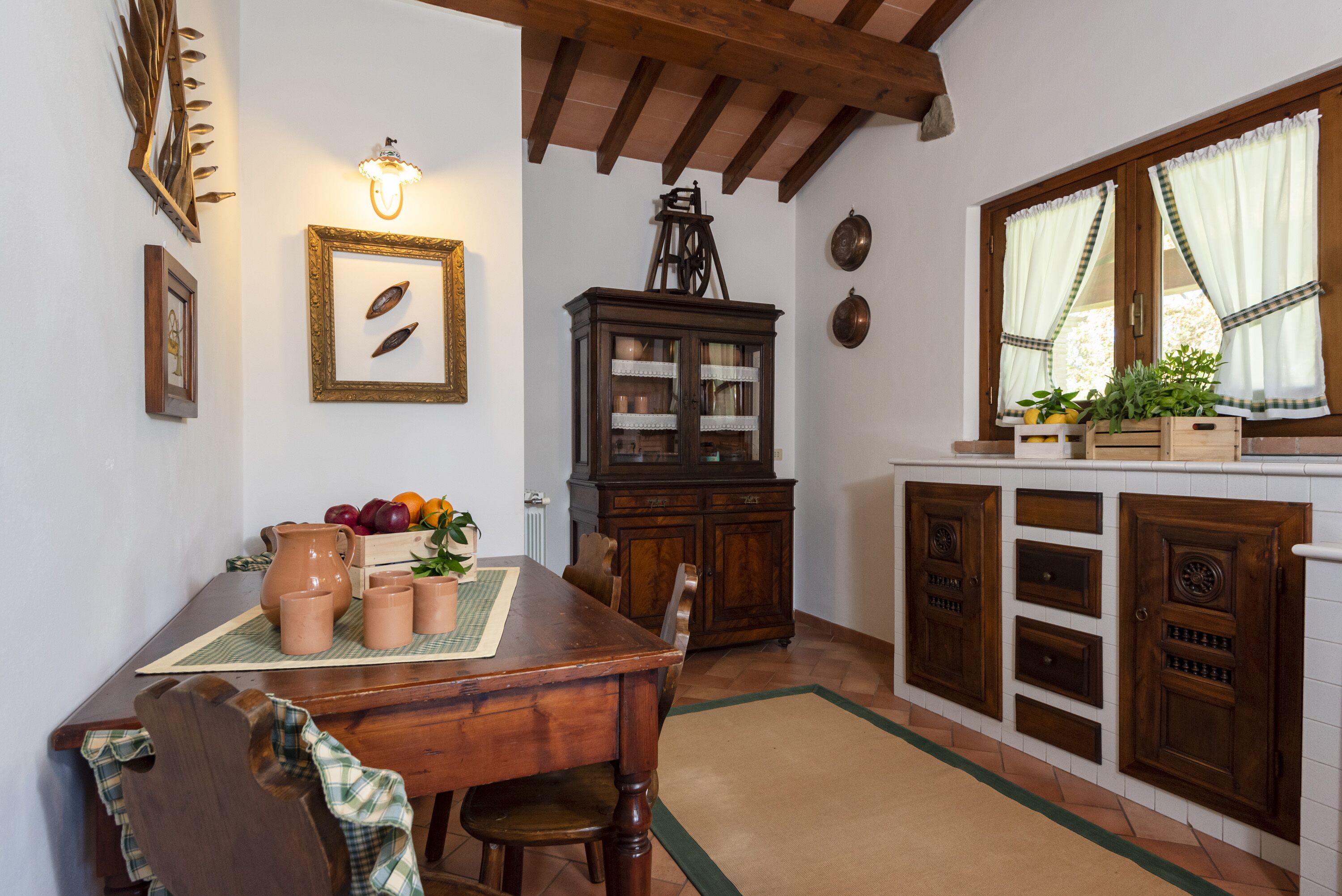 A dining area with a wooden table, chairs, a cabinet, and a window with curtains.