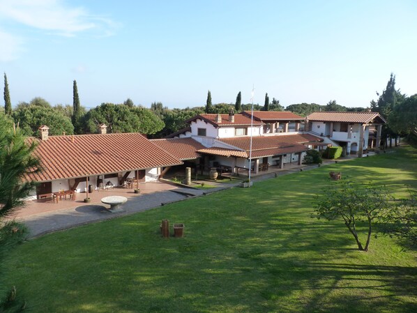 A large, multi-story house with a tiled roof, surrounded by a well-maintained lawn and trees. - Agriturismo La Rombaia (Castiglione della Pescaia)
