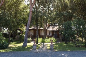 A traditional building with a tiled roof, surrounded by lush greenery and stone pillars. - Agriturismo La Rombaia (Castiglione della Pescaia)