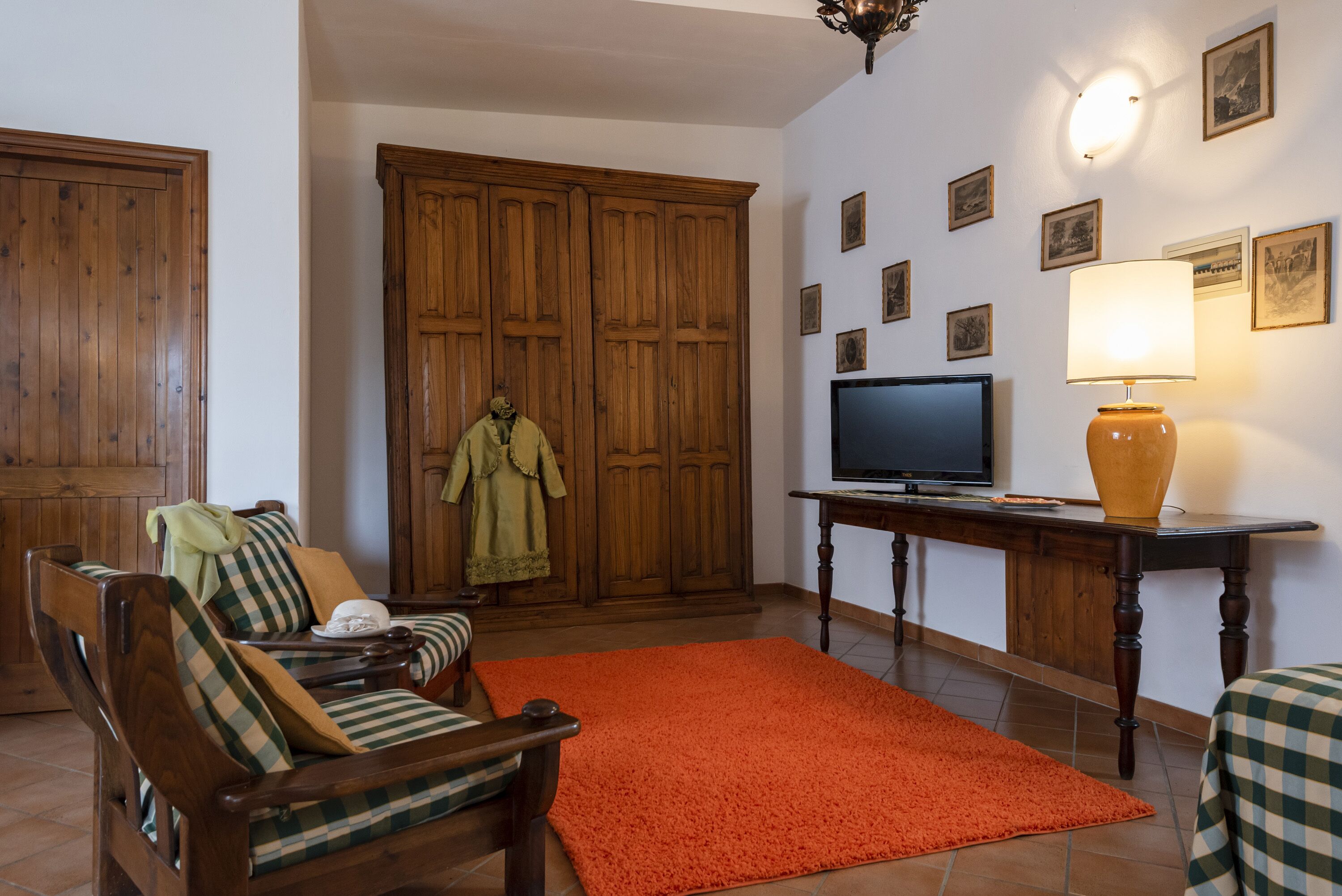 Una sala de estar con muebles de madera, un televisor y una lámpara.