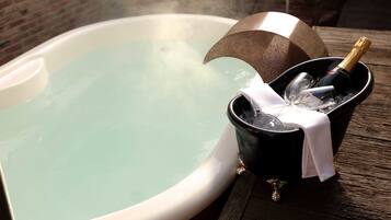 A hot tub with a bottle of champagne and glasses in a bucket.