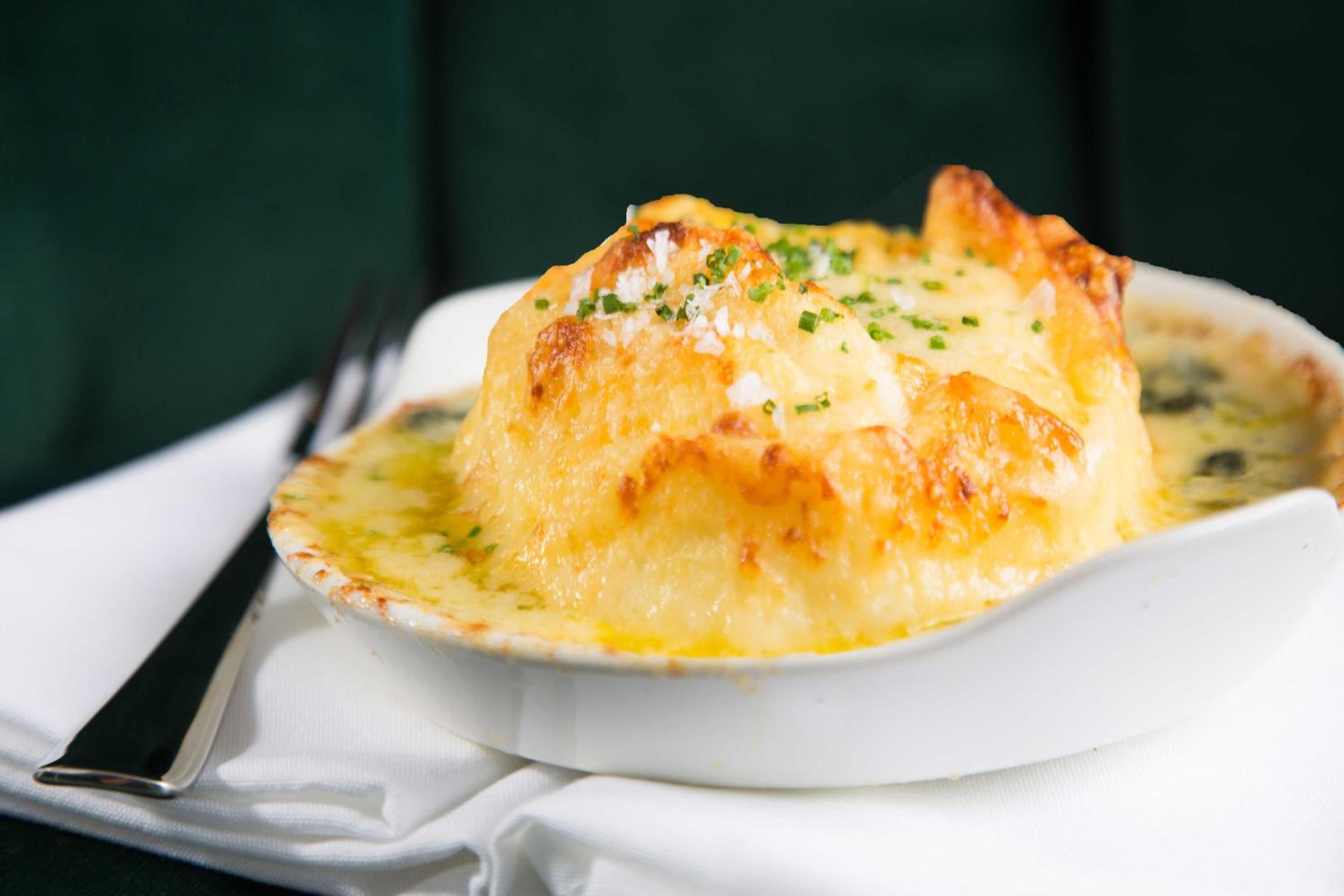 A dish of baked potatoes topped with melted cheese and garnished with chives.