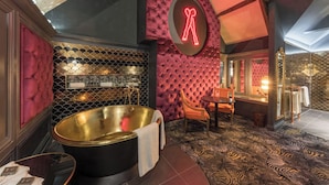 Une salle de bain luxueuse avec une grande baignoire, un miroir et un coin salon.