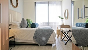 Un dormitorio moderno con cama, mesita de noche y espejo.