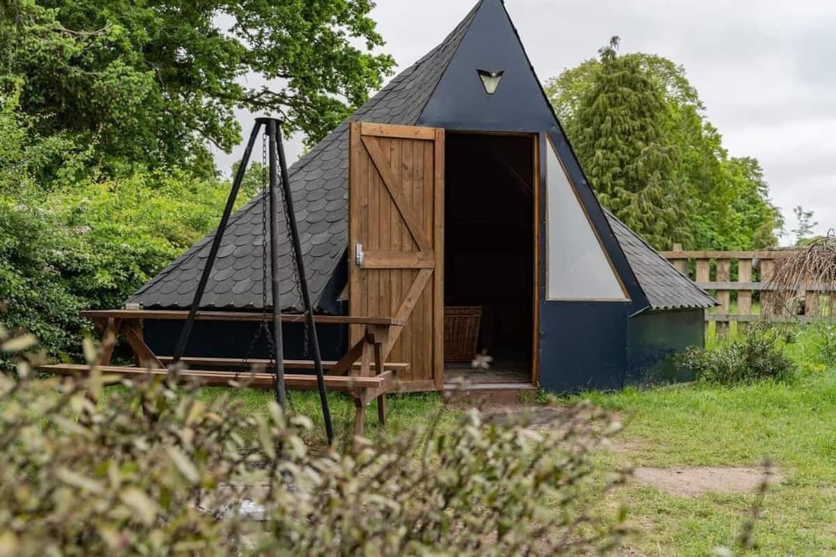 A small, triangular-shaped building with a wooden door and a black roof.