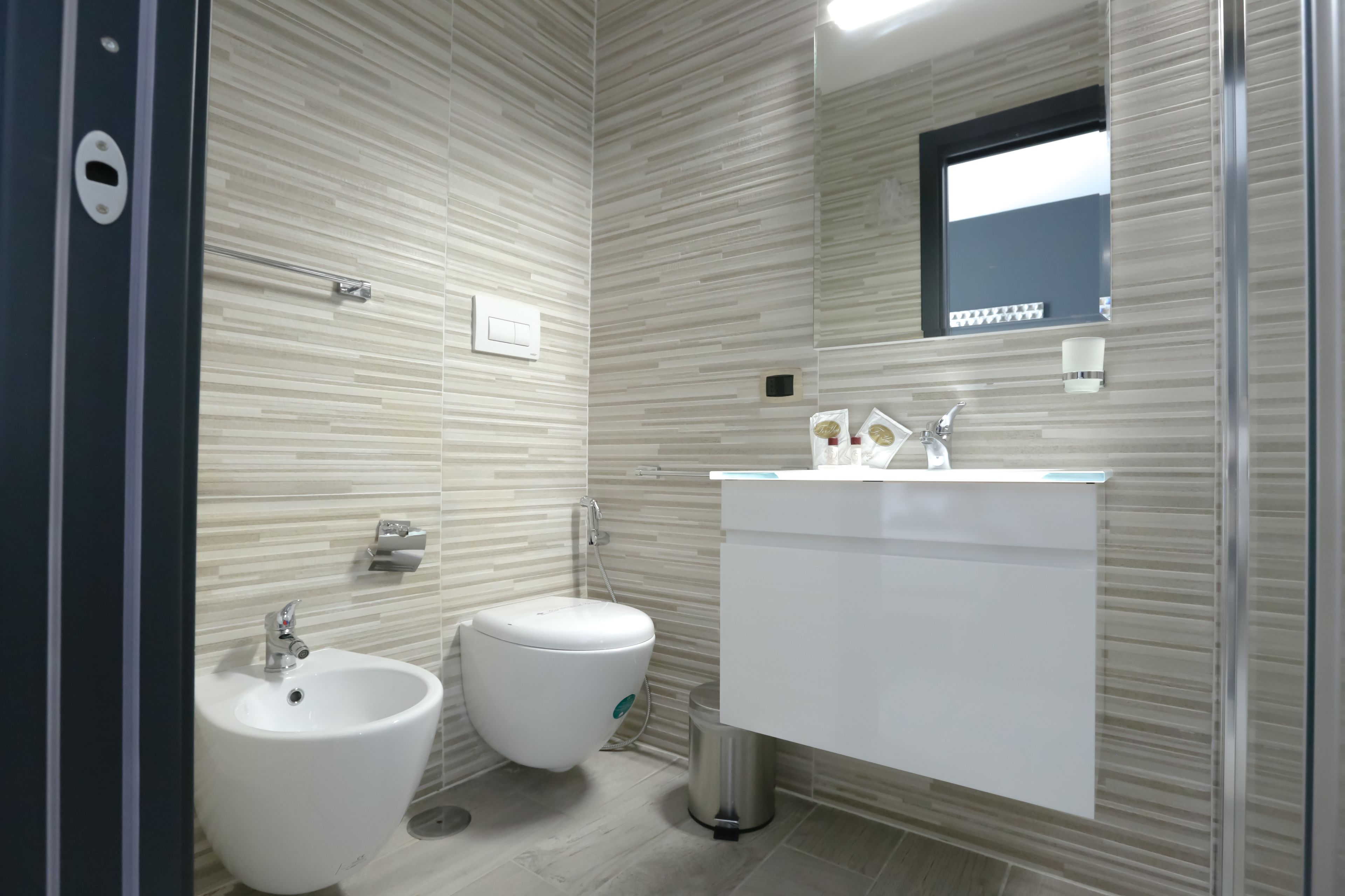Une salle de bain moderne équipée d’un bidet, de toilettes et d’un meuble-lavabo avec un miroir.