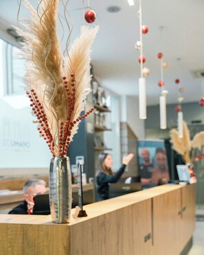 A reception desk with a decorative vase of pampas grass and red berries. - Ecumano Space (Naples)
