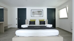 Ein modernes Schlafzimmer mit einem großen Bett, zwei Türen, einem gerahmten Bild über dem Bett und einem Fenster rechts.