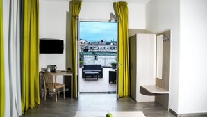 Habitación de hotel moderna con balcón, zona de comedor y televisor en la pared.