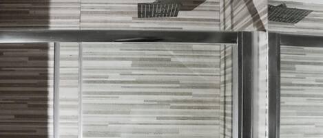 A modern bathroom with a striped tile wall, a metallic faucet, and a glass door.