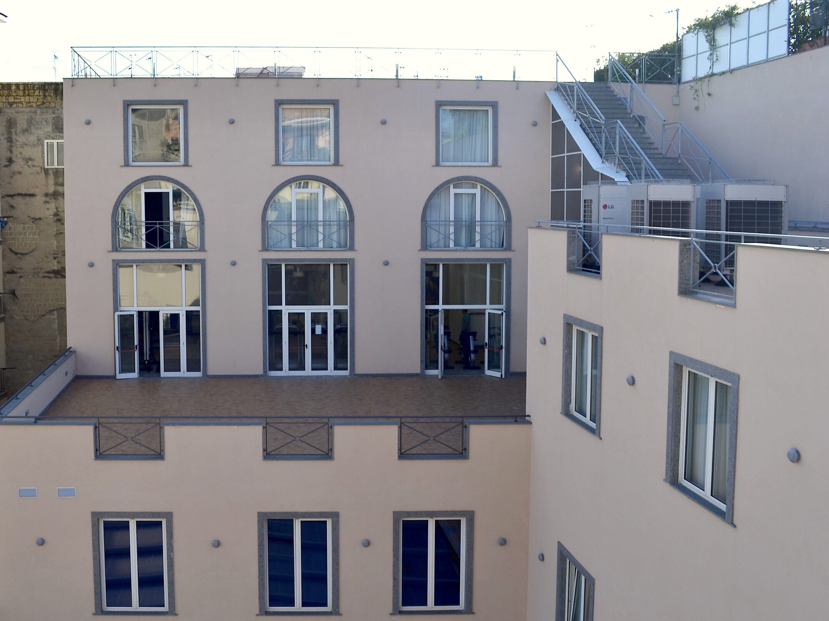 Un edificio a più piani con tetto piano, ampie finestre e una scala antincendio.