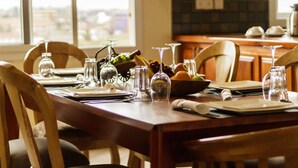 Una mesa de comedor dispuesta con cristalería, platos y un tazón de fruta.