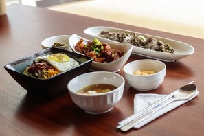 Una mesa con varios platos, incluyendo un tazón de sopa, un tazón de arroz y un plato de carne.