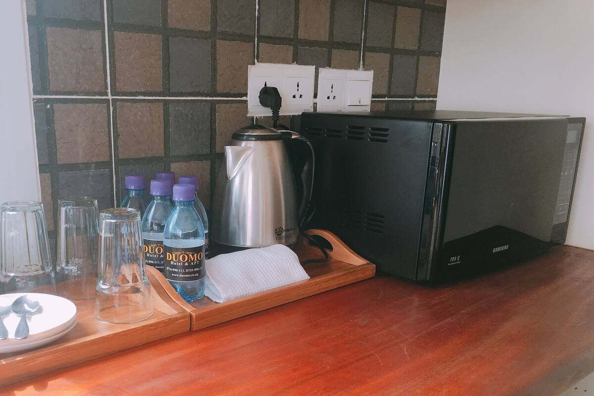 A kitchen counter with a coffee maker, a kettle, and water bottles.
