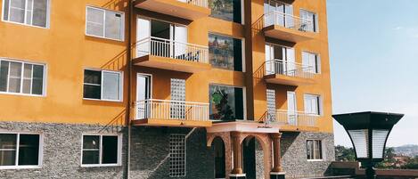 A multi-story hotel with balconies, a swimming pool, and outdoor seating.
