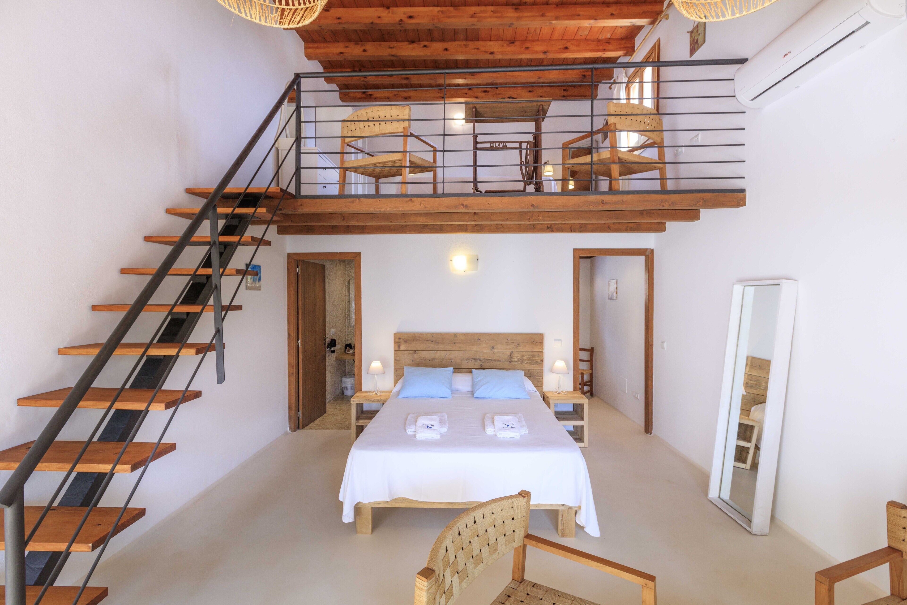 Un dormitorio con una cama grande, una escalera de madera y una zona superior con asientos.