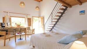 A bedroom with a bed, a desk, chairs, and a staircase. - Es Pas Formentera Agroturismo (Formentera)