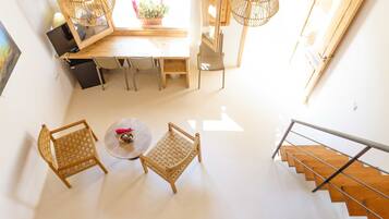 Una habitación de hotel moderna con una escalera de madera, una zona de comedor con mesa y sillas, y vistas al exterior.