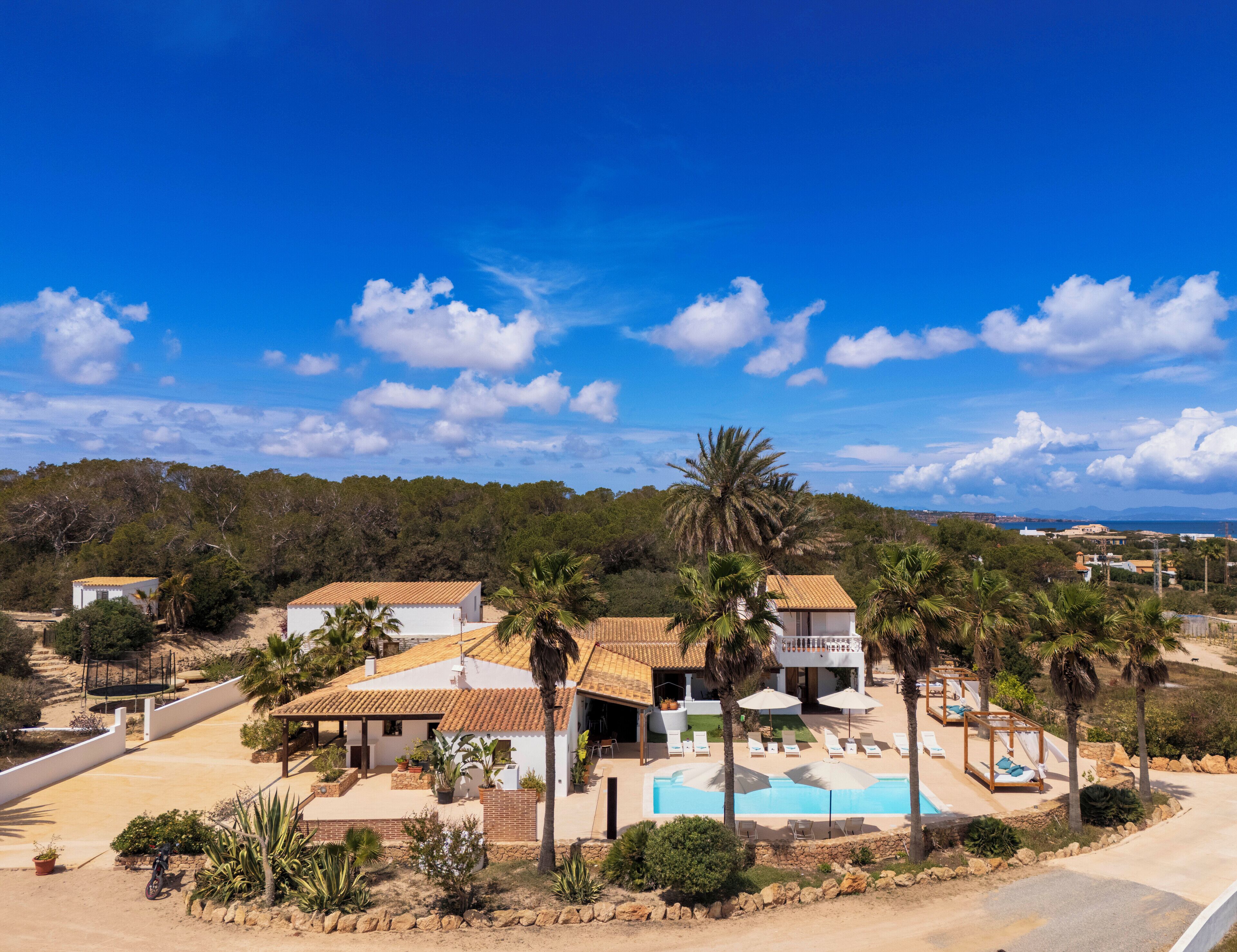 A resort with multiple villas, a swimming pool, and palm trees.