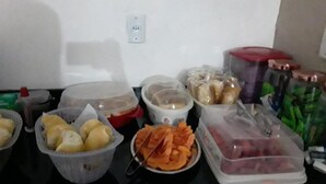 A kitchen counter with various food items and containers, including baskets of bread, a bowl of sliced vegetables, and jars with lids. - Hotel Flex In (Osasco)