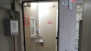 A corridor with a glass door leading to a room. There is a sign on the wall and a fire alarm on the ceiling. - Hotel Flex In (Osasco)