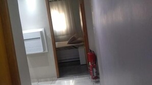A room with a bed, a window with blinds, a fire extinguisher, and a tiled floor. - Hotel Flex In (Osasco)