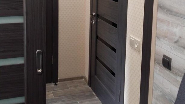 A hallway with a dark wooden door and a light-colored wall. - Hostel Voyage (Kyiv)