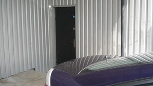 A car parked in a garage with a metal wall and a door. - Hostel Voyage (Kyiv)