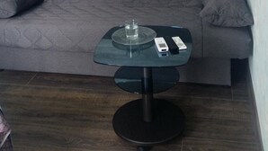 A modern living room with a grey sofa, a glass-top coffee table, and a dark wooden floor. - Hostel Voyage (Kyiv)