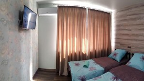 A hotel room with a bed, a TV, and curtains. - Hostel Voyage (Kyiv)