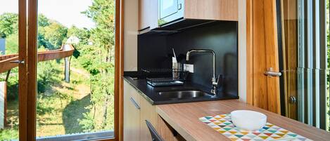 A modern kitchen with a large window, wooden cabinets, a black countertop, and a sink.