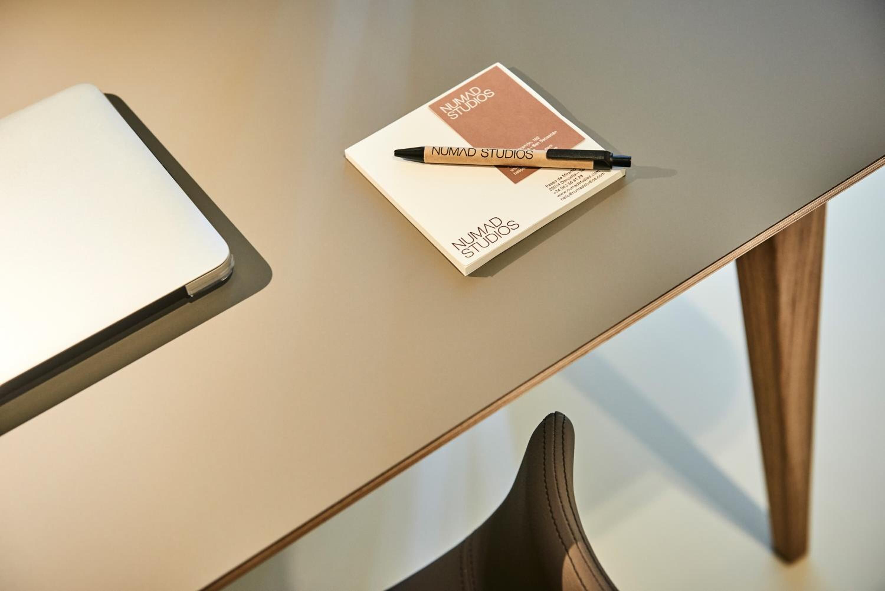 A laptop, a pen, and a business card on a table.