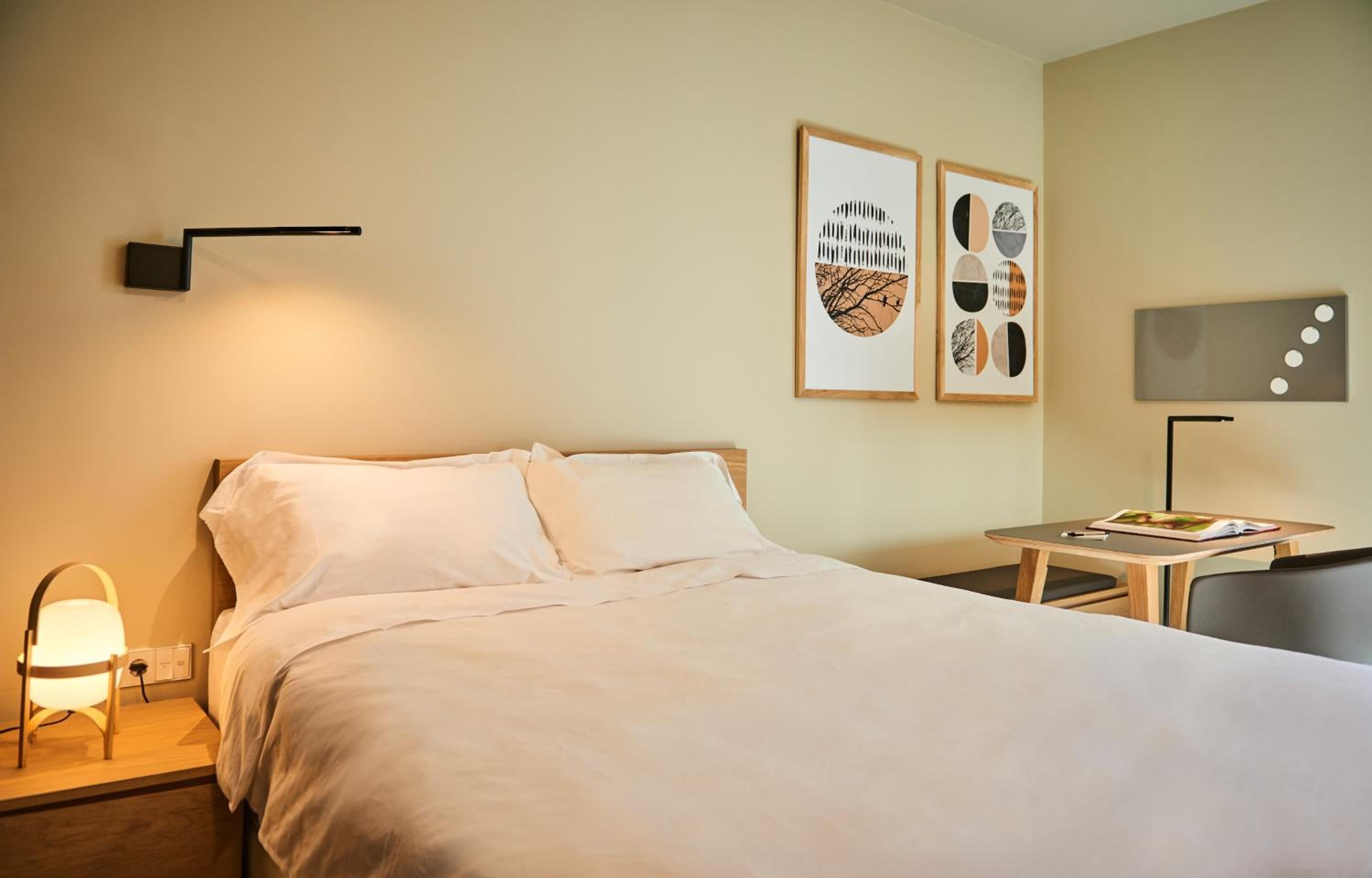Habitación de hotel con cama, mesita de noche, lámpara y decoración en la pared.