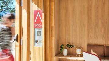 Un intérieur moderne avec un mur lambrissé en bois, un comptoir d’accueil, un espace détente et une enseigne indiquant « NUMAD STUDIOS ».